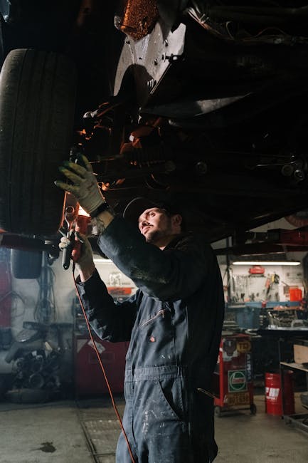 Mechanic working on a car maintenance in a well-equipped garage setting.